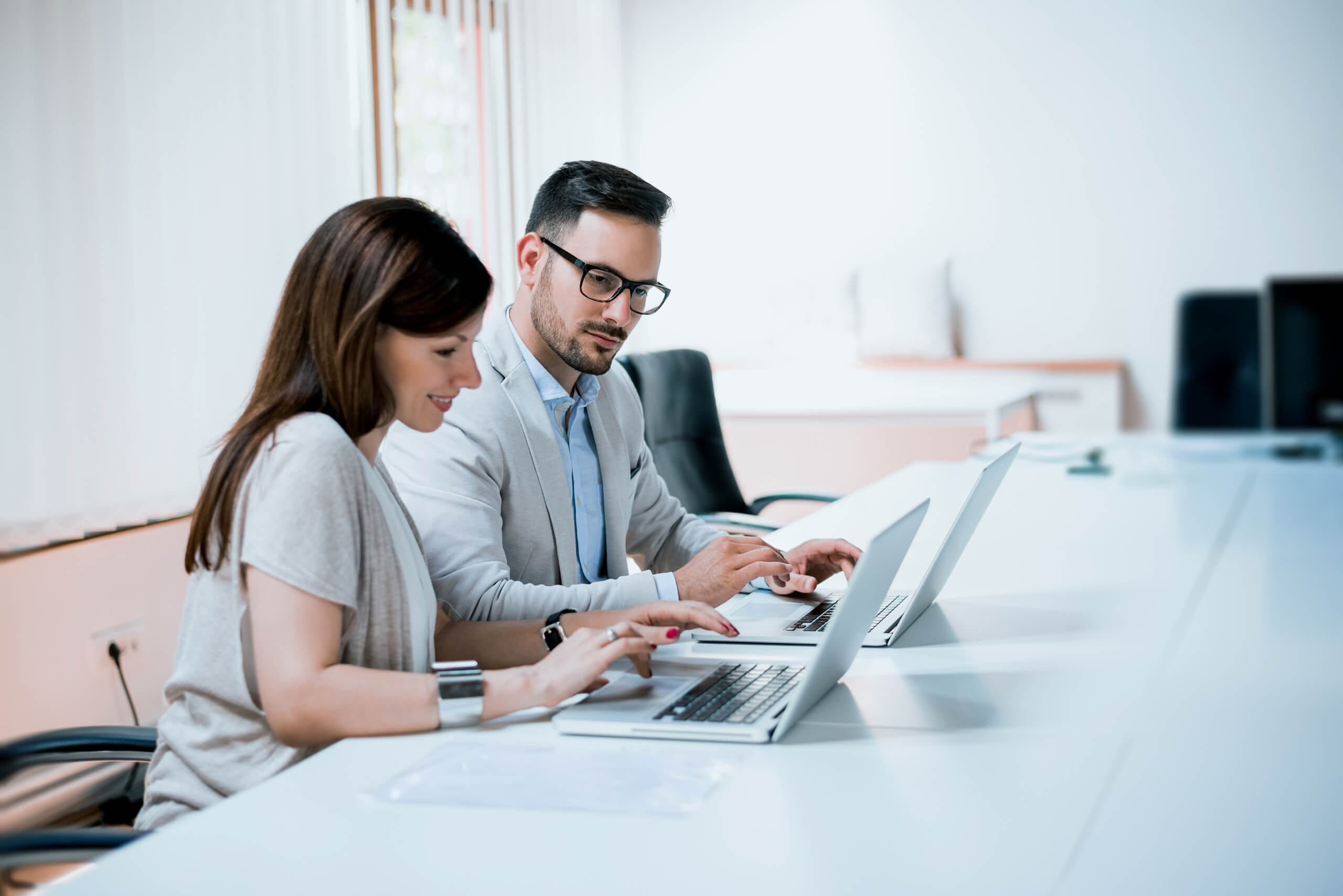 Two business people working together on laptops