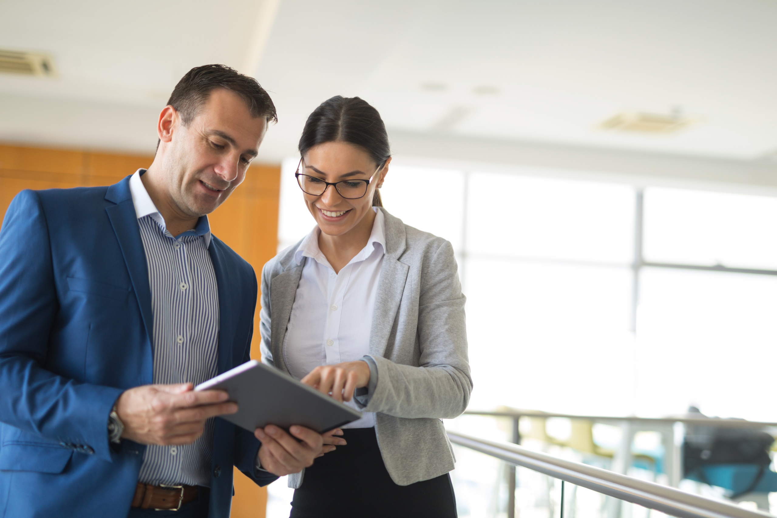 Mann und Frau stehen im Büro mit Tablet in der Hand
